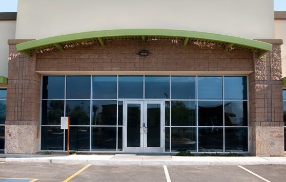 The entrance to a retail storefront with glass double doors and a green awning.