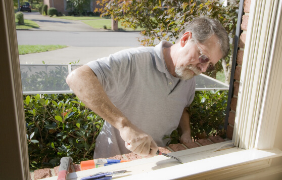 A man using a chisel to repair a window frame.